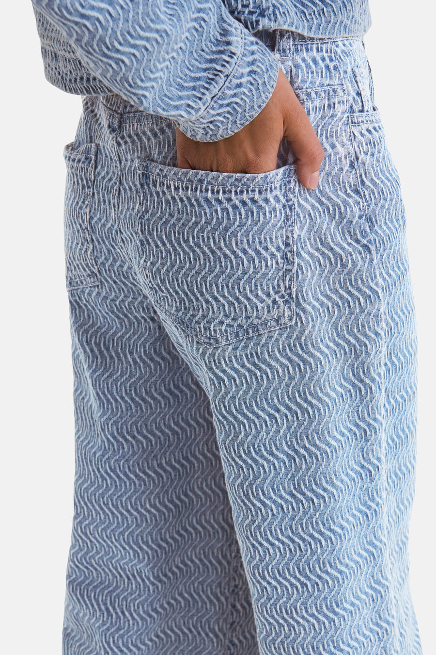 Jean coloré en denim bleu clair de JDY, avec un motif ondulé texturé, main dans la poche arrière.
