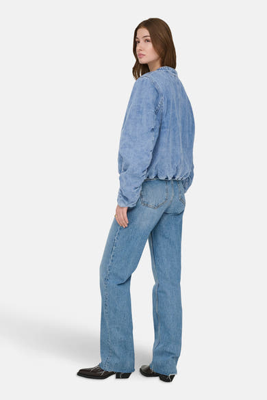 Middelblauwe spijkerjas van ONLY® gedragen met een bijpassende spijkerbroek en zwarte schoenen.