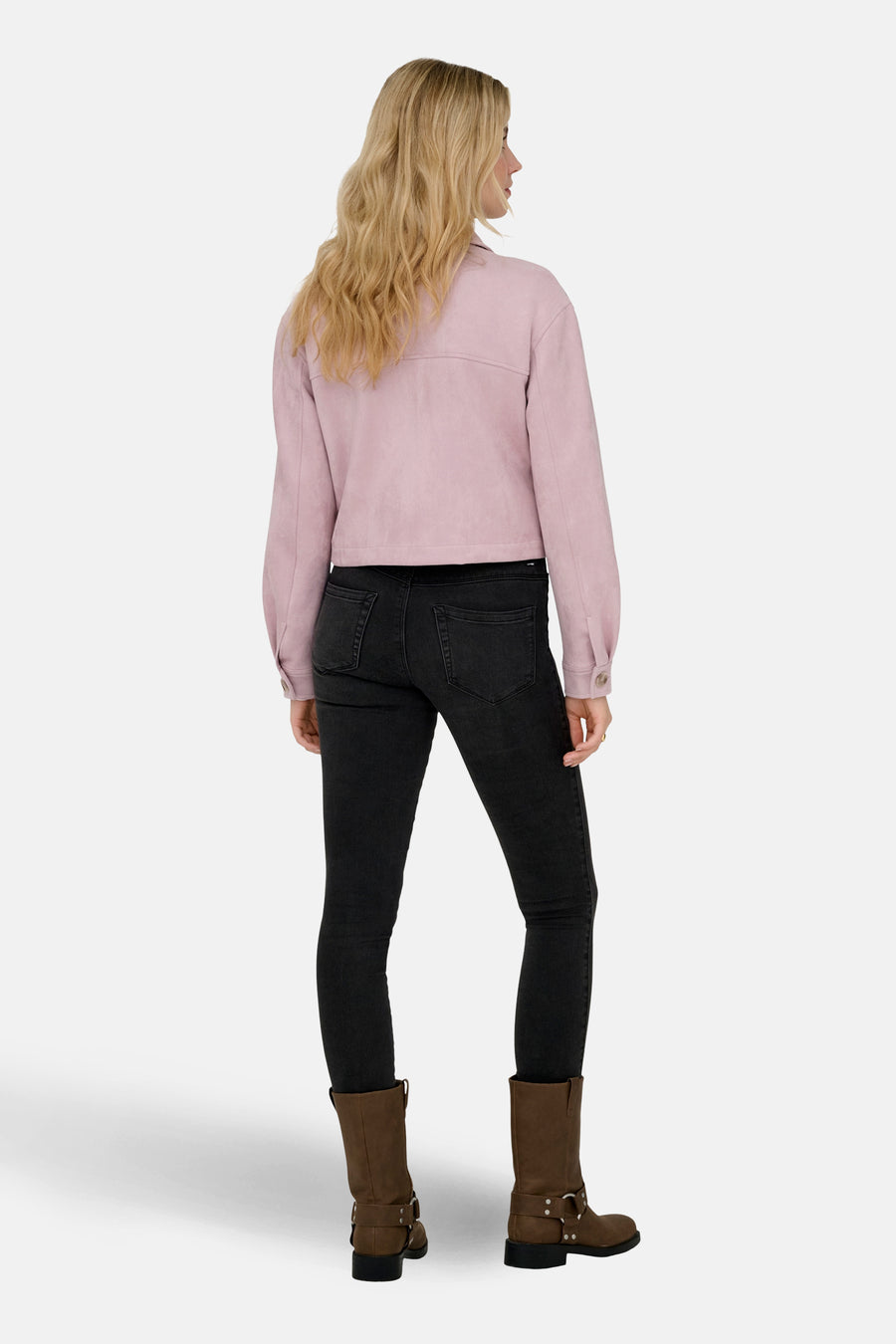 Kort roze suèdejasje van ONLY®, gedragen met een zwarte jeans en bruine laarzen, van achteren gezien.