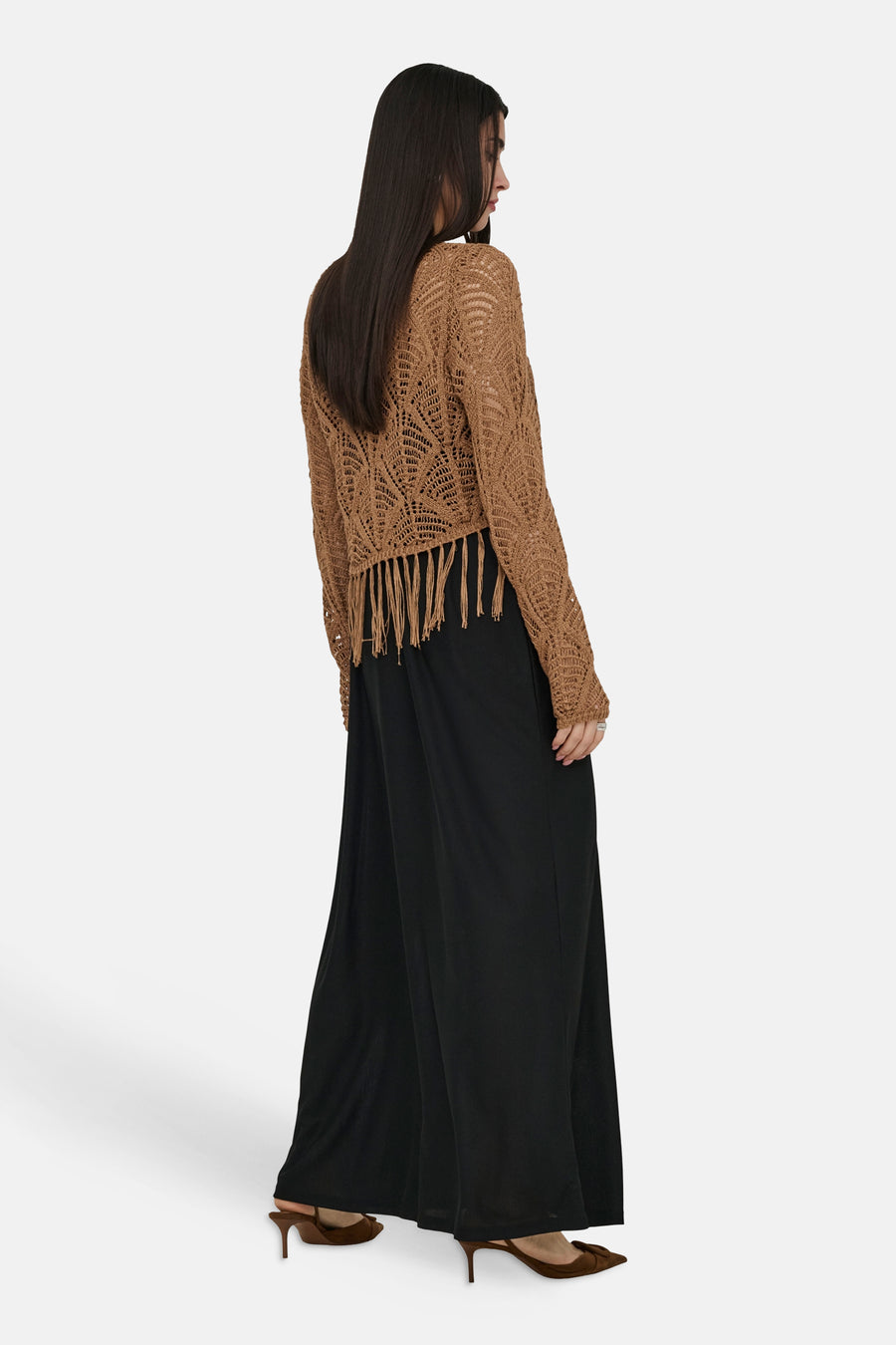 Bruine TRICOT® met ajourpatroon en franjes, gedragen met een wijde zwarte broek en bruine pumps.
