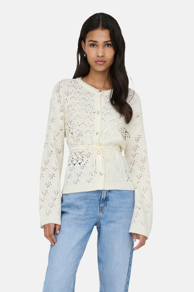 Ecru gilet van ONLY, gedragen met een geknoopte riem, op een wijde blauwe jeans en zwarte schoenen.