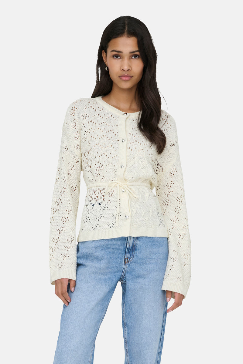 Ecru gilet van ONLY, gedragen met een geknoopte riem, op een wijde blauwe jeans en zwarte schoenen.