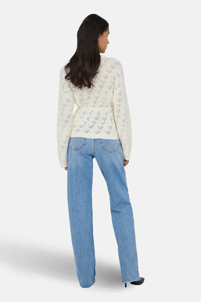 Ecru vest van ONLY, in open gebreide stof, gedragen met een wijde blauwe jeans.