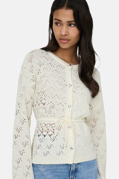 Gilet écru en maille ajourée de ONLY, avec ceinture à nouer et boutons décoratifs en forme de cœur.