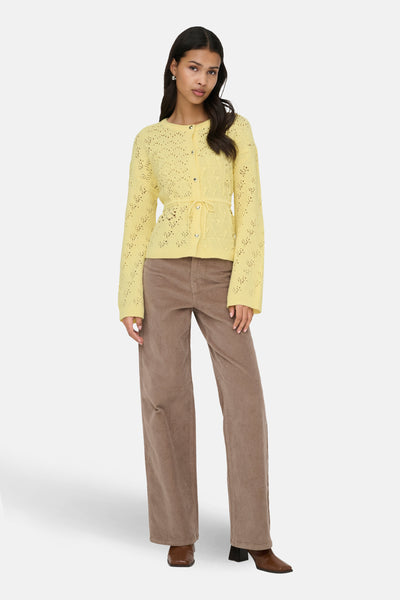 Gilet jaune by ONLY avec motif ajouré, ceinture à nouer et manches longues, porté avec un pantalon marron en velours côtelé.