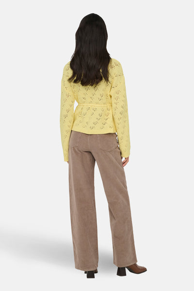 Geel gebreid vest met open structuur van ONLY, gedragen met een corduroy broek en bruine enkellaarsjes.
