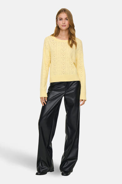 Pull à col rond jaune de ONLY® avec motif ajouré, porté avec un pantalon en similicuir noir.
