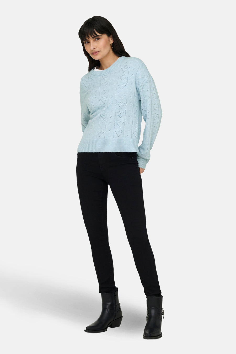 Pull à col rond bleu clair par ONLY, avec un motif ajouré, porté avec un pantalon noir et des bottes.
