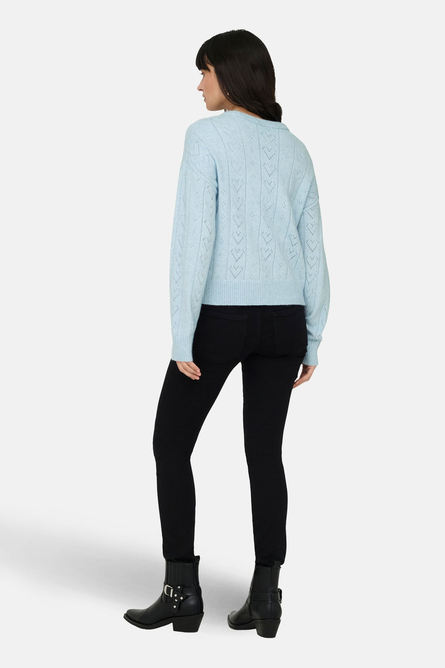 Ronde hals trui blauw van ONLY, met hartvormig ajourpatroon, gedragen met een zwarte broek en enkellaarsjes.