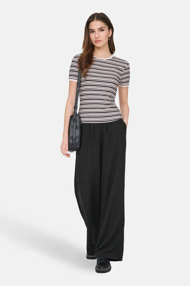 T-shirt à manches courtes multicolore de JDY, rayures horizontales, porté avec un pantalon noir ample et un sac à bandoulière.