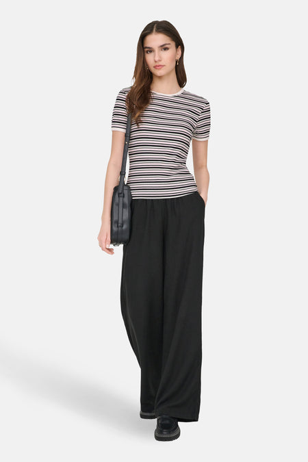T-shirt à manches courtes multicolore de JDY, rayures horizontales, porté avec un pantalon noir ample et un sac à bandoulière.