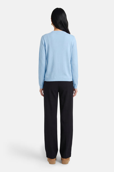 Cardigan bleu clair de JDY, porté avec un pantalon noir ample et des chaussures à plateforme marron, vue de dos.
