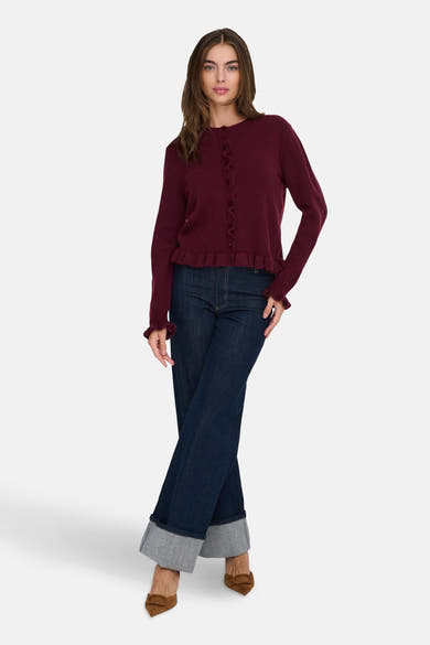 Cardigan bordeaux en maille fine de JDY, avec boutons et détails à volants, porté avec un jean taille haute.
