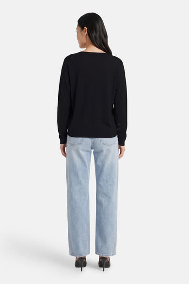 Zwarte V-hals trui van JDY, gedragen met een blauwe jeans en zwarte hakken, achtergezicht.