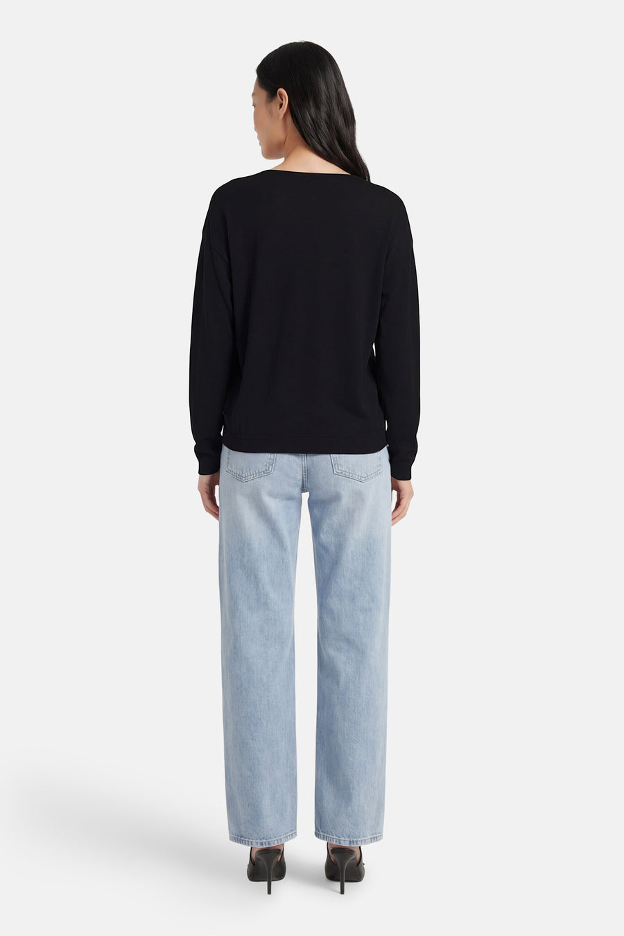 Zwarte V-hals trui van JDY, gedragen met een blauwe jeans en zwarte hakken, achtergezicht.