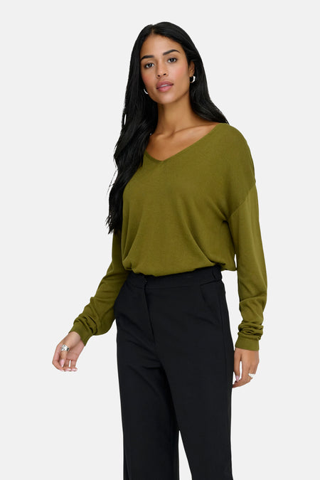 Groene V-hals trui van JDY, gedragen met een wijde zwarte broek.