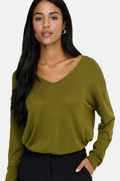 Groene V-hals trui van JDY, gedragen met een zwarte broek en zilveren oorbellen.
