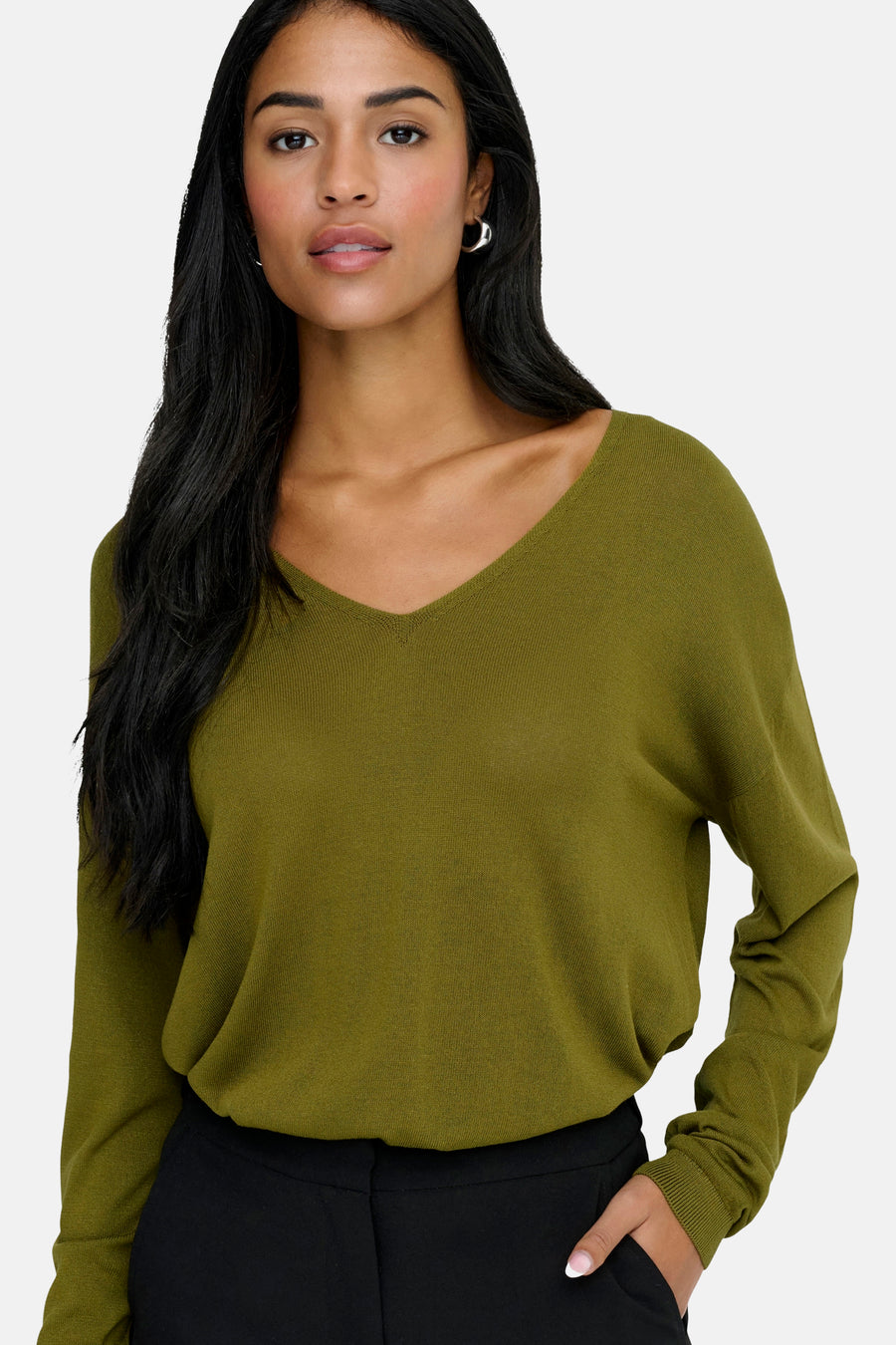 Groene V-hals trui van JDY, gedragen met een zwarte broek en zilveren oorbellen.