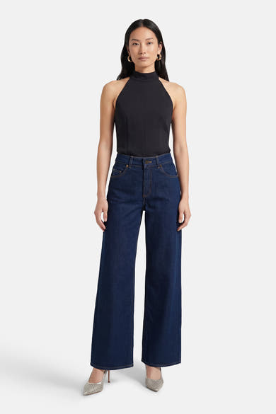 Jean large bleu moyen de ONLY, porté avec un haut noir sans manches et des escarpins brillants.
