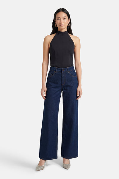 Jean large bleu moyen de ONLY, porté avec un haut noir sans manches et des escarpins brillants.
