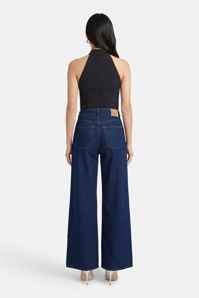 Jean large en denim bleu moyen de ONLY®, vue de dos, porté avec un haut noir uni.
