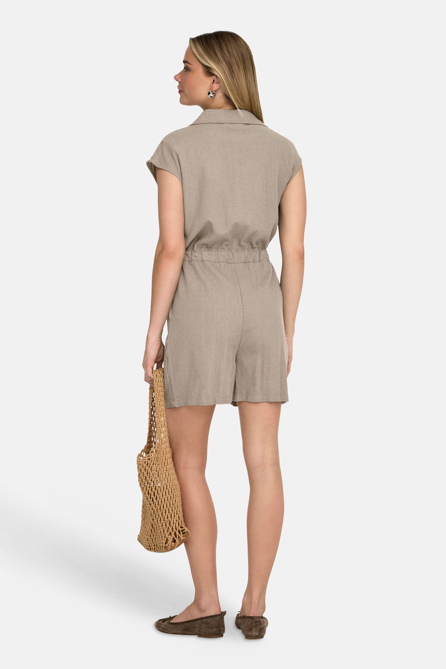 Combi-short beige, par ONLY®, avec une ceinture élastique, porté avec un sac en filet marron et des chaussures plates.