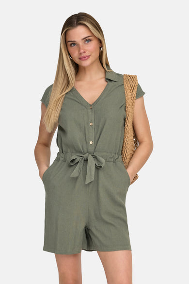 Kaki combishort van ONLY, met een strikceintuur in de taille en gedragen met bruine ballerina's en een gehaakte boodschappentas.