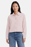 Veste en jean rose pâle de ONLY® à coupe courte, avec boutons argentés et poches poitrine, portée avec un jean bleu.