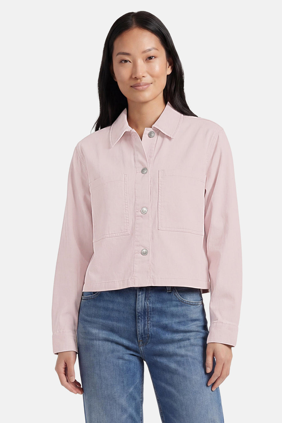 Veste en jean rose pâle de ONLY® à coupe courte, avec boutons argentés et poches poitrine, portée avec un jean bleu.
