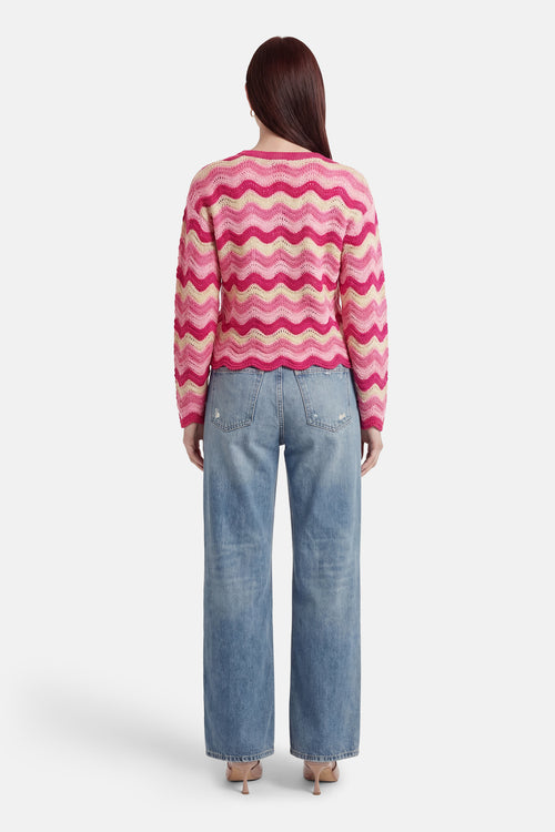 Pull à col rond rose par ONLY®, à rayures vagues rose clair et jaune, porté avec un jean bleu ample.