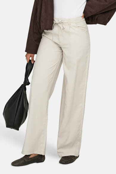 Jeans coloré écru de ONLY®, à coupe large avec cordon de serrage, porté avec un sac noir.