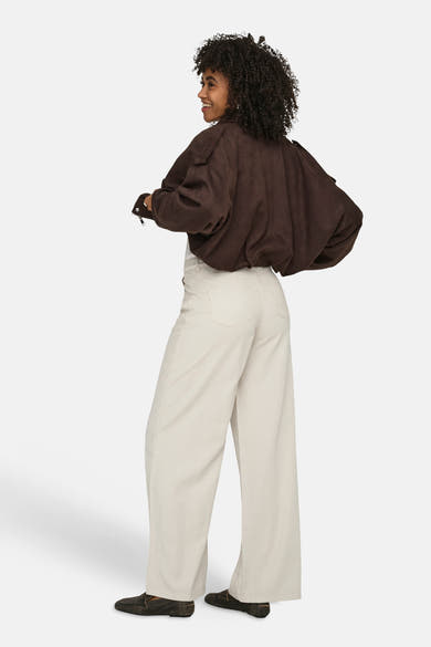 Jeans écru de ONLY® à coupe large, porté de dos avec une veste marron et des mocassins.