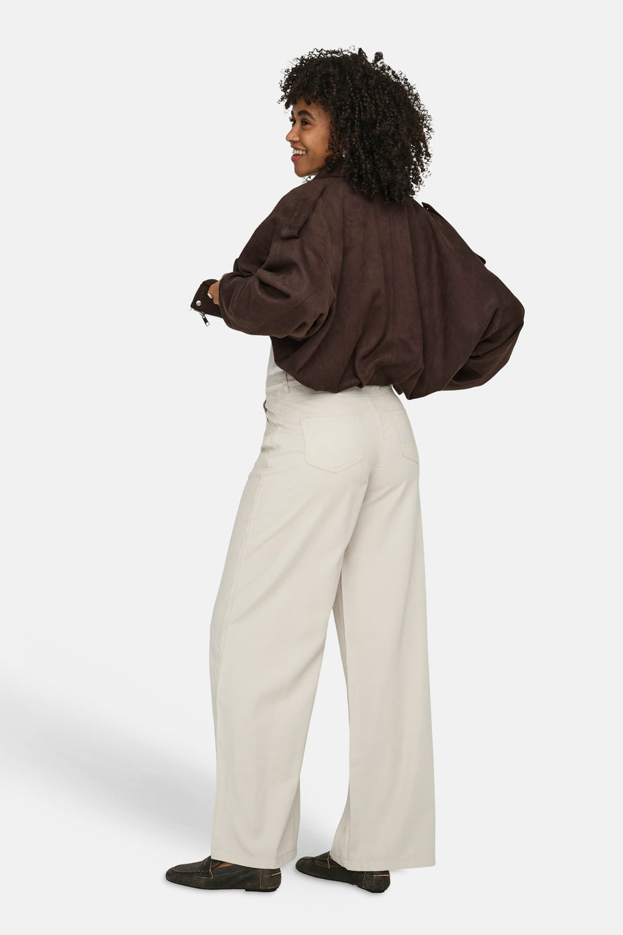 Jeans écru de ONLY® à coupe large, porté de dos avec une veste marron et des mocassins.