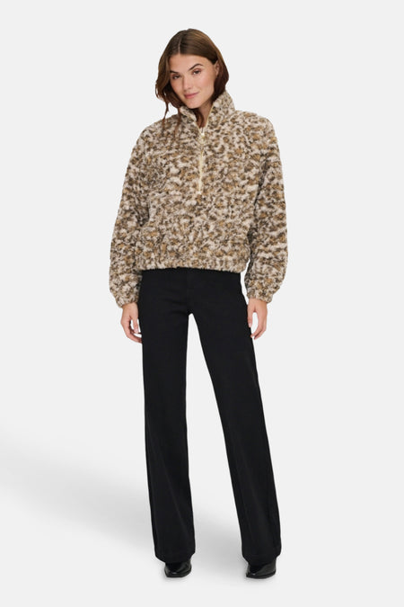 Veste courte en fausse fourrure beige de ONLY, avec fermeture éclair et pantalon noir.
