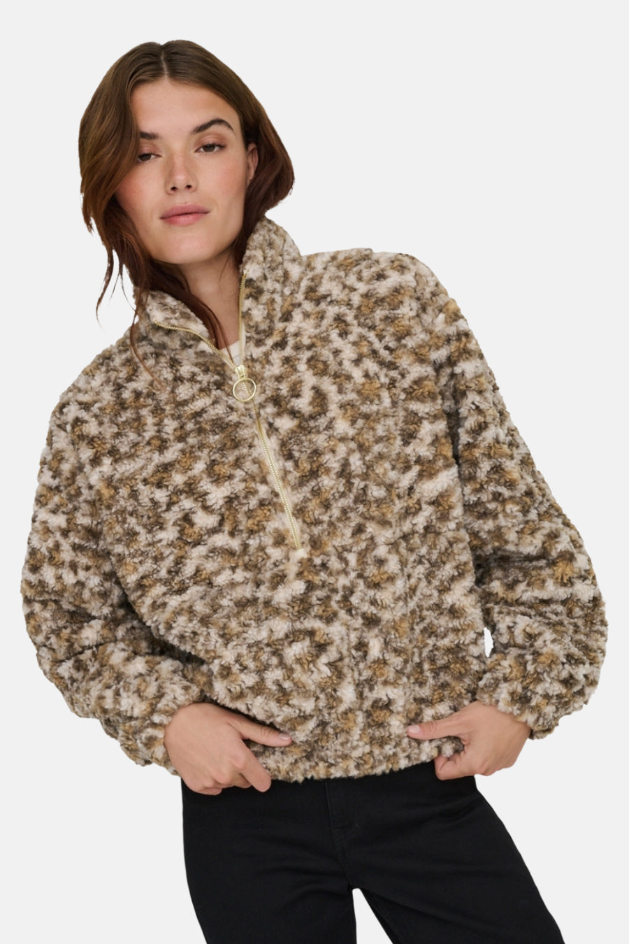 Korte beige jas van pluizige stof van ONLY, met gouden ritssluiting aan de voorkant en gedragen over een zwarte broek.