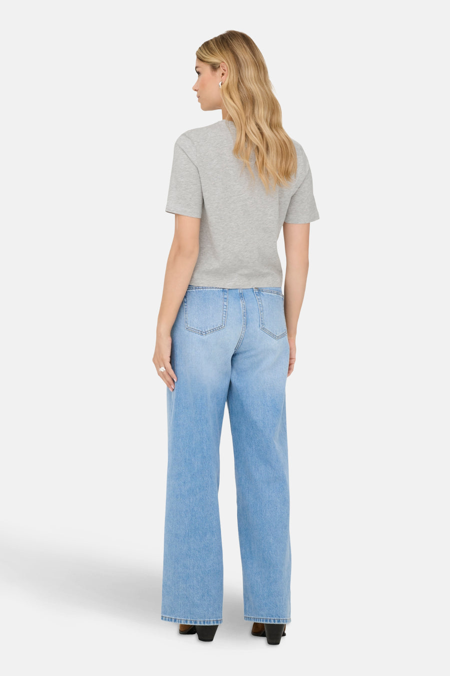 Grijs T-shirt met korte mouwen van ONLY, gedragen met een wijde blauwe jeans en bruine enkellaarsjes.
