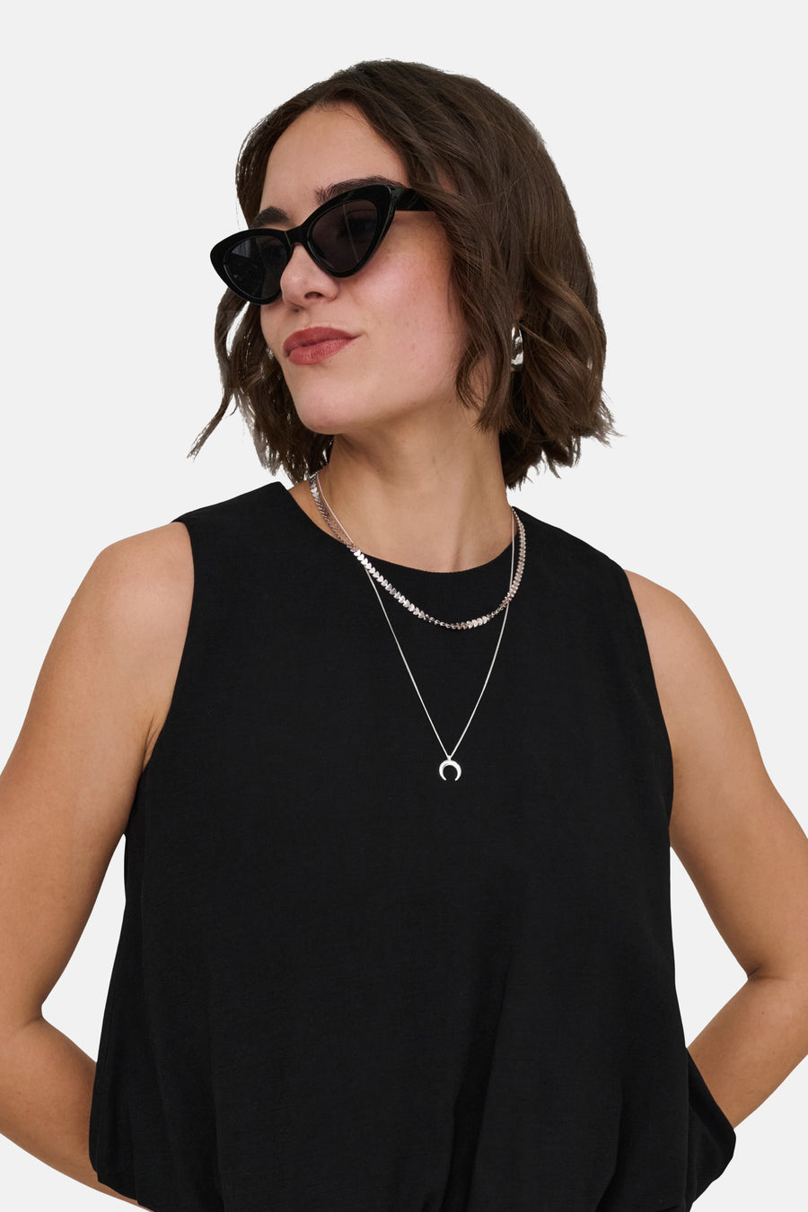 Top noir sans manches de ONLY®, porté par une femme avec des lunettes de soleil et des colliers argentés dont un avec pendentif lune.