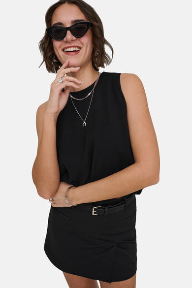 Top sans manches noir de ONLY, fluide, porté avec une ceinture, une mini-jupe et des bijoux argentés.