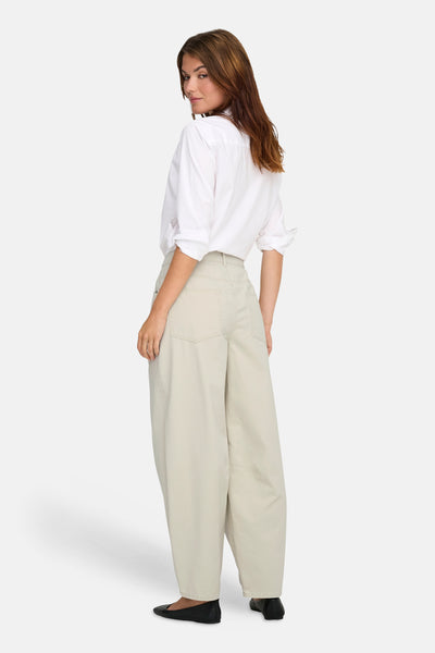 Pantalon écru van ONLY®, porté avec une chemise blanche à manches longues et des chaussures plates noires.