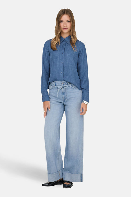 Jean large en denim bleu clair de ONLY, porté avec une chemise et des ballerines noires.
