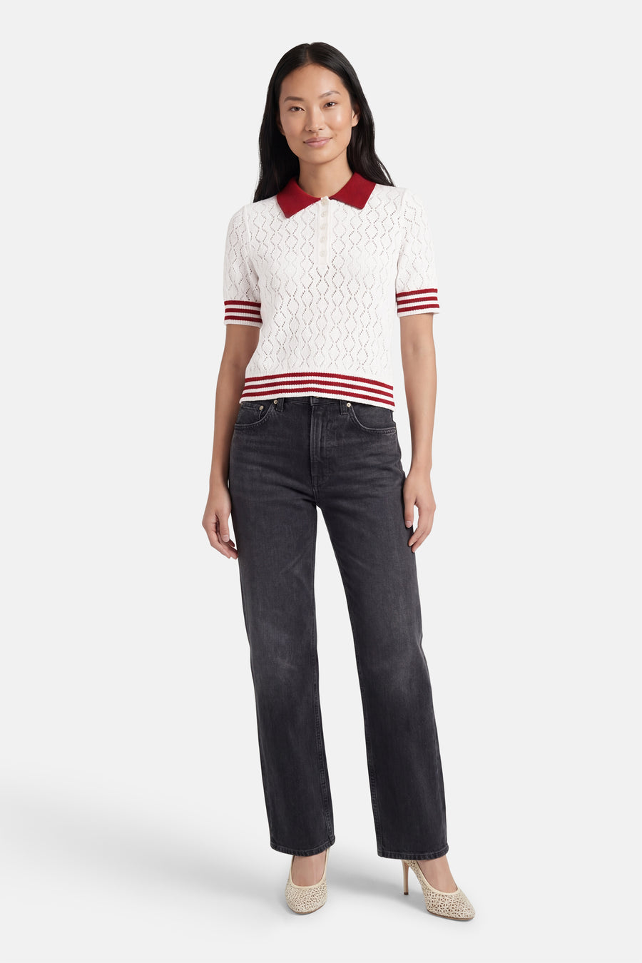 Wit gebreid vest met ajourpatroon van het merk ONLY, met rode polokraag en rode strepen. Gedragen met een grijze jeans en lichte ajour pumps.
