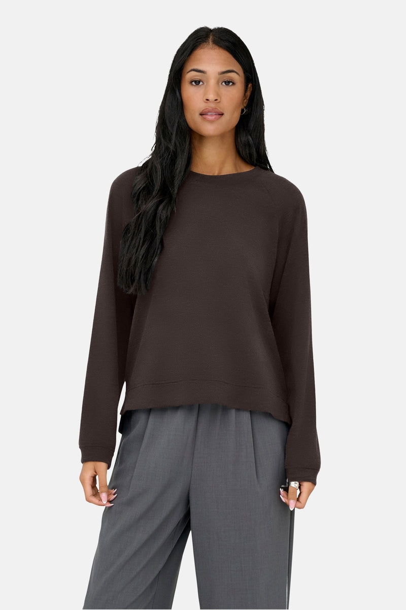 Bruine ronde kraag pull van ONLY, gedragen met een ruime grijs broek, rugweergave.