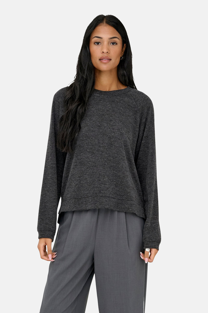 Grijze rondehals trui van ONLY, gedragen met een grijze broek met hoge taille en zwarte schoenen.