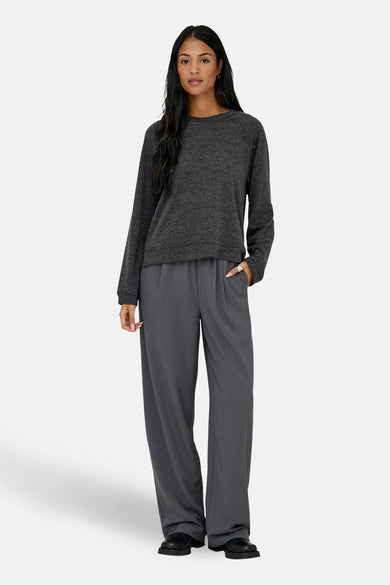 Pull à col rond gris par ONLY, porté avec un pantalon gris taille haute et des chaussures noires.