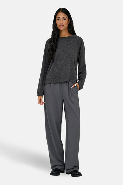 Pull à col rond gris par ONLY, porté avec un pantalon gris taille haute et des chaussures noires.