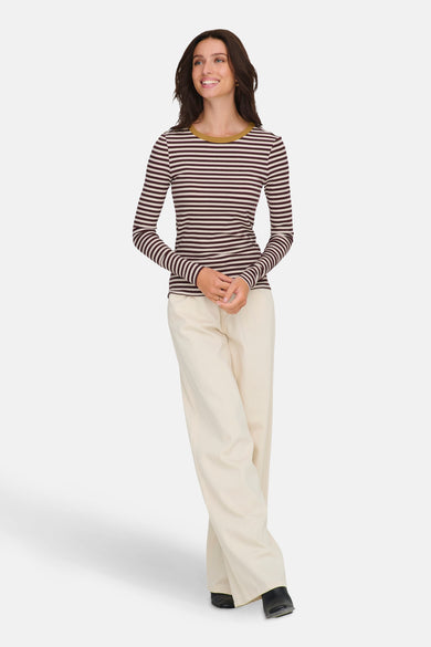 T-shirt à manches longues bordeaux rayé de ONLY, porté avec un pantalon beige ample et des chaussures noires.