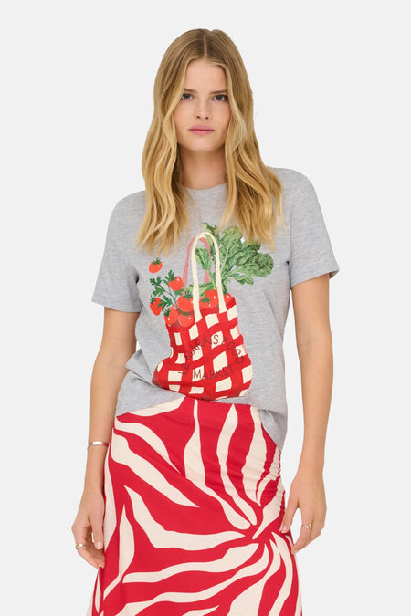 T-shirt gris chiné de ONLY®, avec un imprimé sac de marché rouge et blanc, porté avec une jupe à motifs zébrés rouges et beiges.
