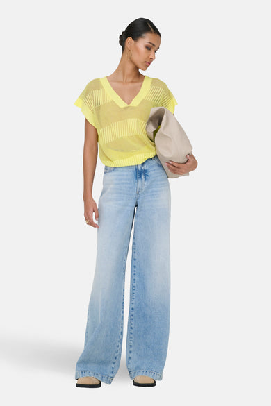 Débardeur jaune en maille ajourée de ONLY, porté avec un jean ample bleu et un sac beige.
