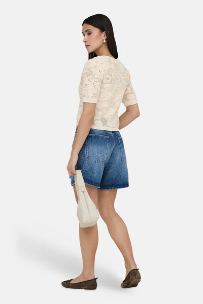 Ecru vest van ONLY®, in ajourbreisel, gedragen met een spijkerbroekshort en bruine ballerina's.
