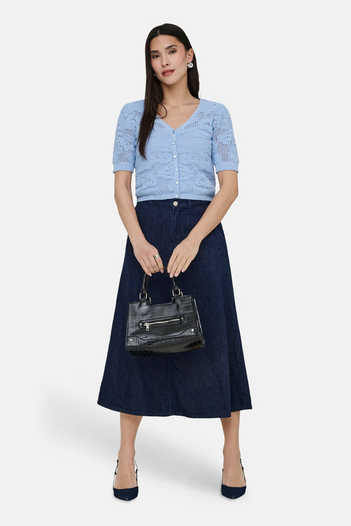 Gilet bleu en maille ajourée de ONLY, porté avec une jupe longue en jean et des escarpins.
